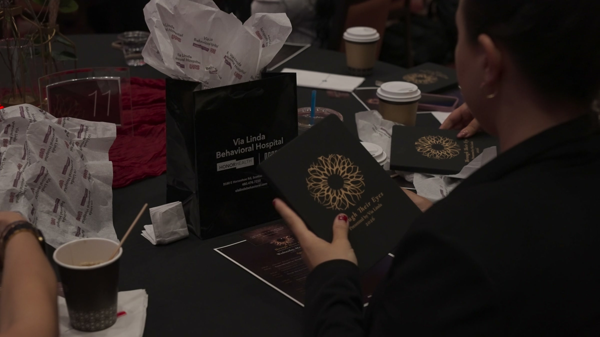 An attendee holding the event journal, the gold mark embossed on its black cover