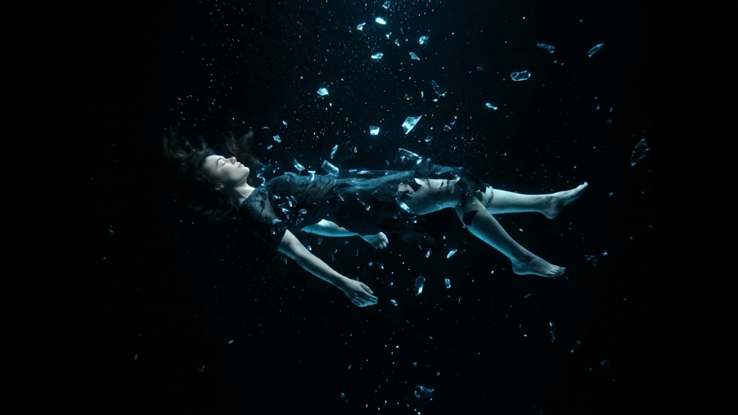 A figure suspended underwater in cold blue light